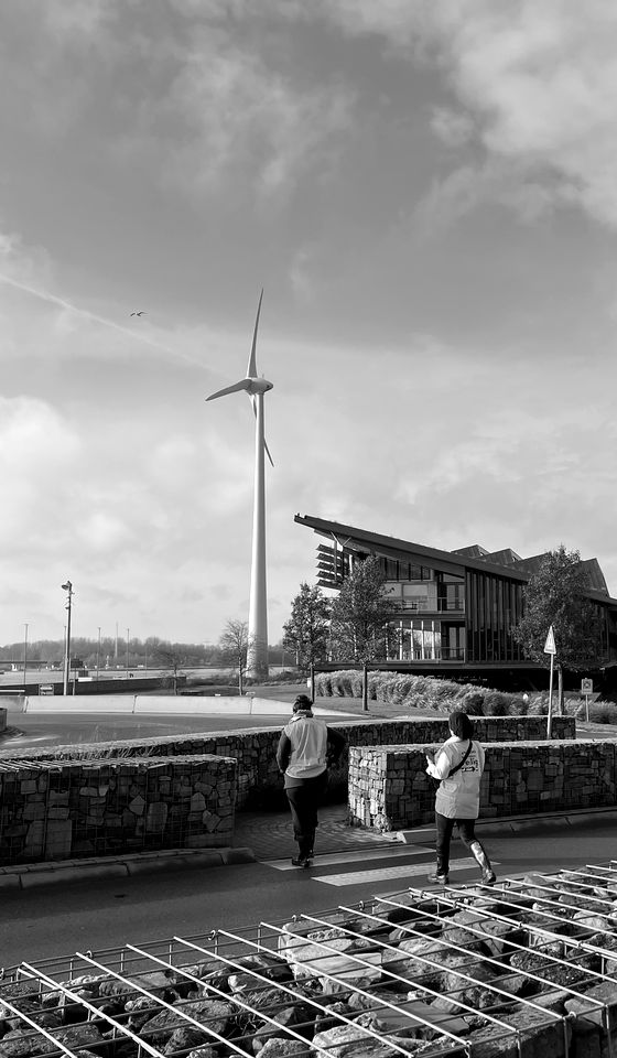 Aerogenerador junto a una instalación, con personas caminando en primer plano