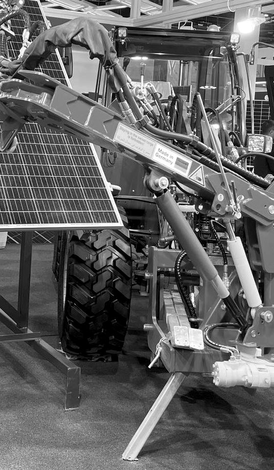 Maquinaria pesada con un brazo mecánico junto a paneles solares