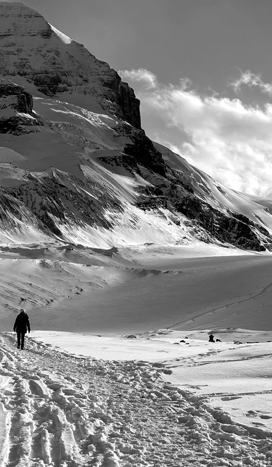 Un caminante cruza un valle de montaña cubierto de nieve
